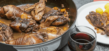 Coq au vin et un verre de vin rouge