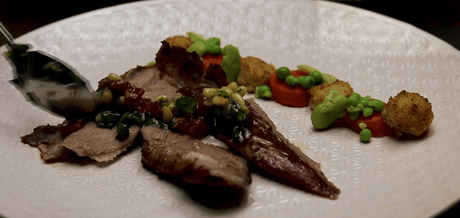 Épaule d'agneau sauce vierge découpée sur une assiette blanche