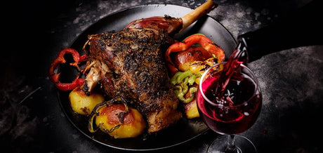 Gigot d'agneau rôti avec des pommes de terre, des poivron et du vin rouge